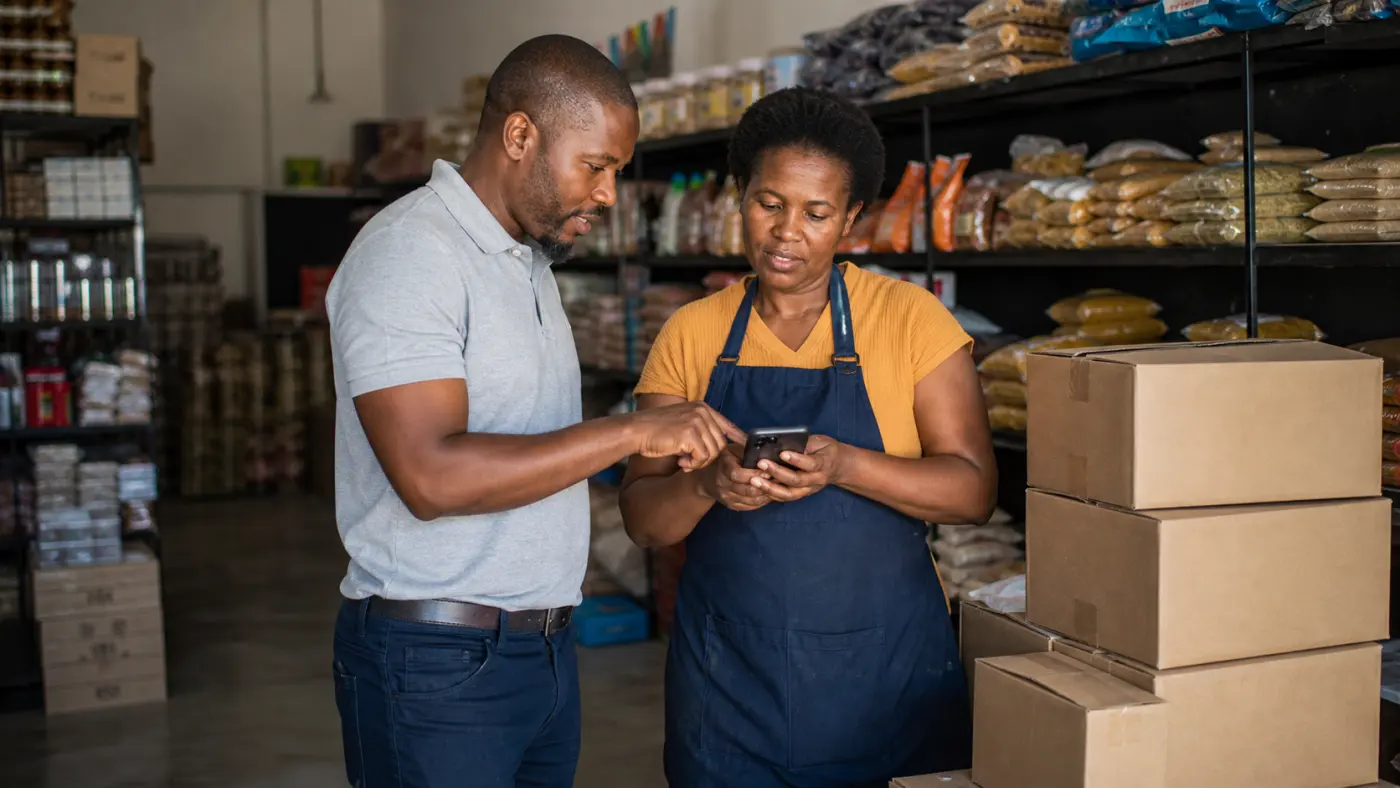 Wholesale sales representative helping a South African shop owner place a mobile order